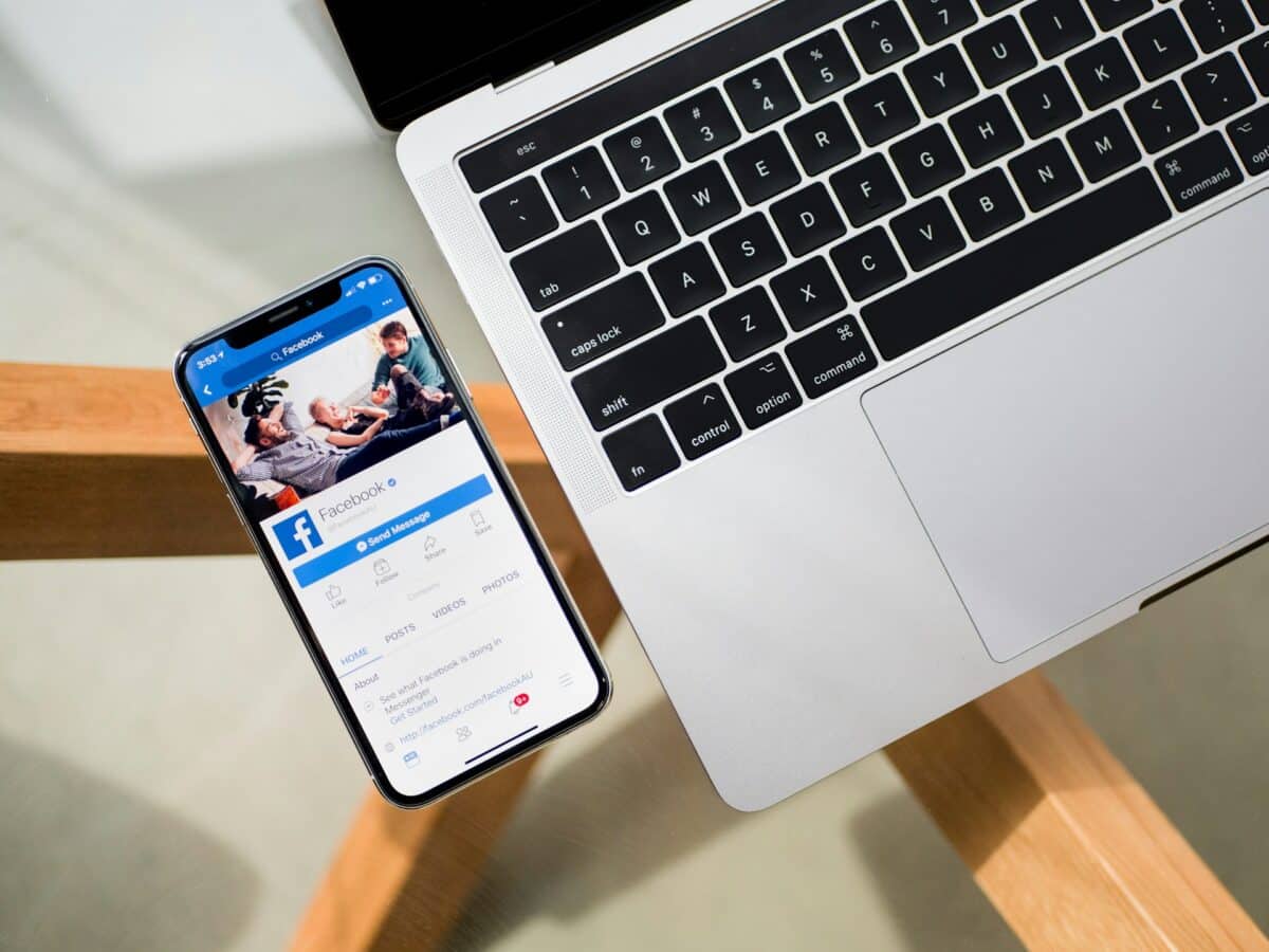 Smartphone showing Facebook next to laptop