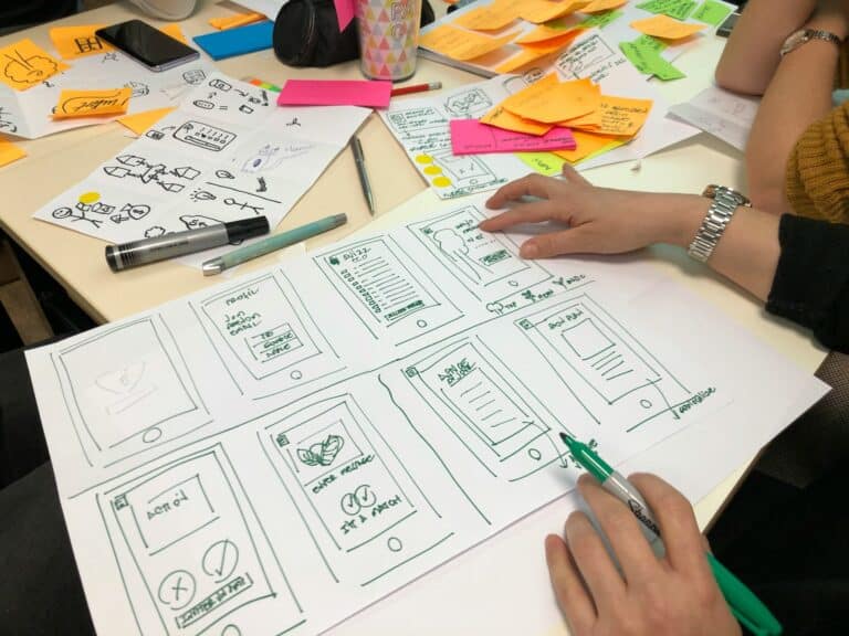 Team designing mobile app wireframes on paper