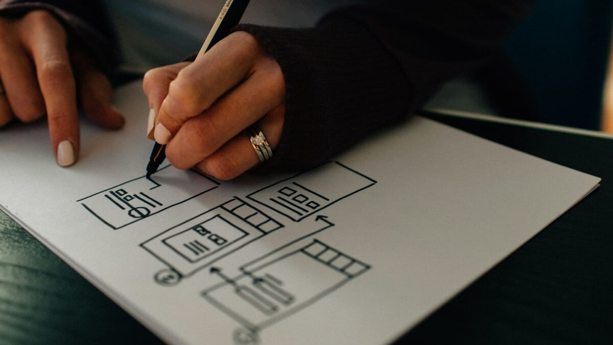 Person sketching website wireframe design on paper